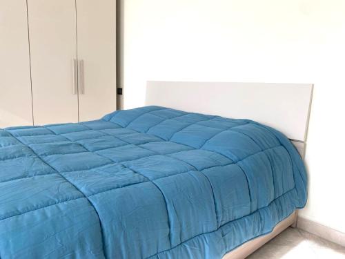 a bed with a blue comforter in a bedroom at Appartamento Mi & Ti in CastellʼAlfero