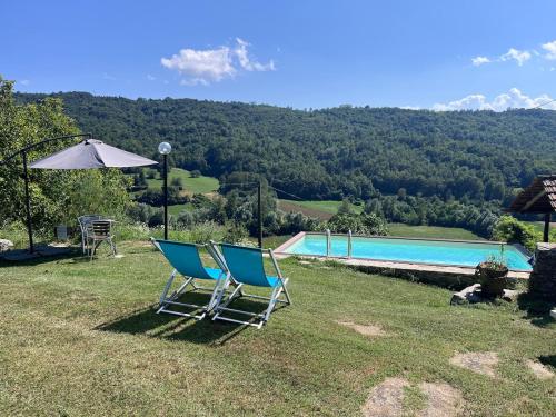 two chairs and an umbrella next to a swimming pool at LUNA dei CARLINI in Mombarcaro