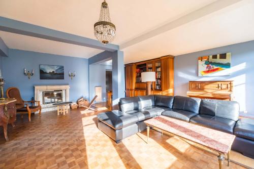 a living room with a leather couch and a fireplace at Maison 8 pers jardin centre ville 15 min de plages in Lannion