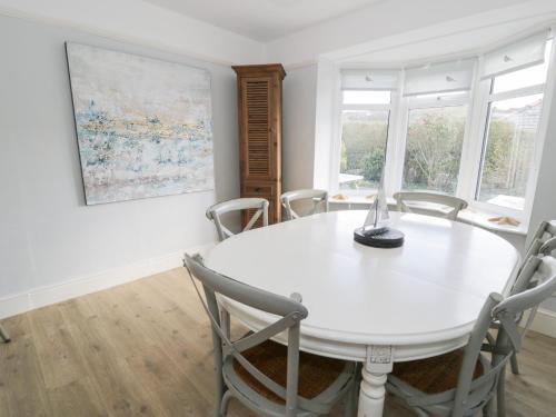 a white dining room with a white table and chairs at Glynmor in Harlech