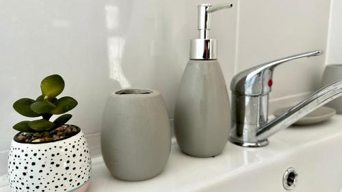two white vases sitting on a sink next to a faucet at Beautyful Resort Apartment in Haifa