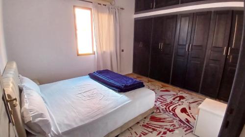 a bedroom with a bed with a blue pillow on it at Residence Rosas in Ouarzazate