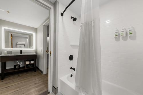 a white bathroom with a shower and a sink at Hawthorn Extended Stay by Wyndham College Station in College Station