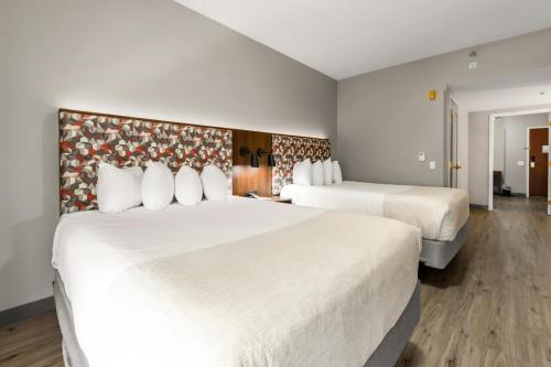 two beds in a hotel room with white sheets at Hawthorn Extended Stay by Wyndham College Station in College Station