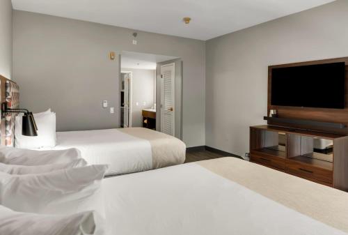 a hotel room with two beds and a flat screen tv at Hawthorn Extended Stay by Wyndham College Station in College Station