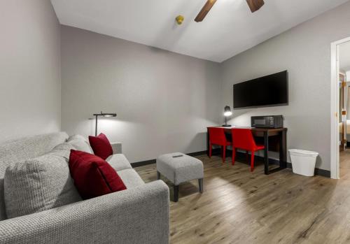a living room with a couch and a table with red chairs at Hawthorn Extended Stay by Wyndham College Station in College Station
