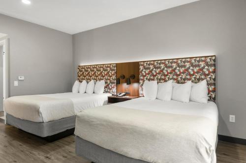a hotel room with two beds and a chair at Hawthorn Extended Stay by Wyndham College Station in College Station