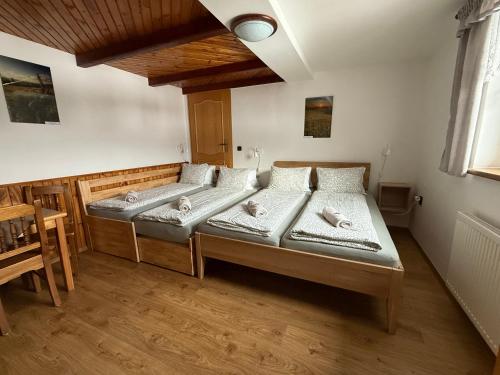 two beds in a room with a wooden floor at Pension Hones in Horská Kvilda