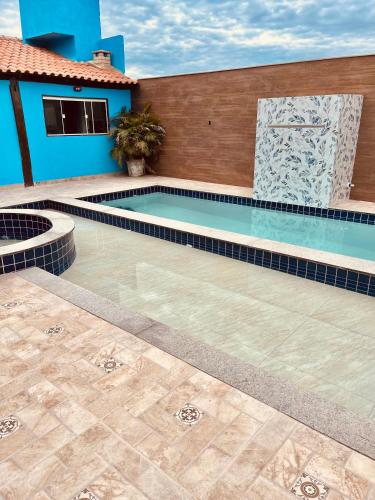 a swimming pool in front of a blue house at Pousada Portal de Búzios in Armacao dos Buzios