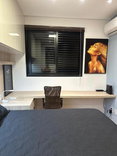 a bedroom with a desk with a picture of a woman at Studio completo e bem localizado in Jaú