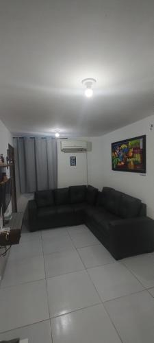 a living room with a black couch in a room at Casa do Léo 1- México e África- Apartamento completo perto das praias do litoral sul , Ar condicionado ,Wi-Fi, garagem, churrasqueira e pet friendly in João Pessoa