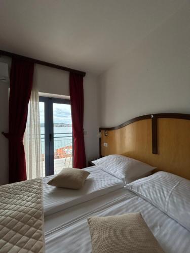 a bedroom with two beds and a large window at Hotel Bavaria Trogir in Trogir