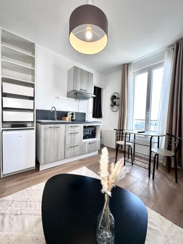 une cuisine et une salle à manger avec un vase sur une table dans l'établissement Charmant appartement proche Paris Champs Élysées - Wifi, à Asnières-sur-Seine