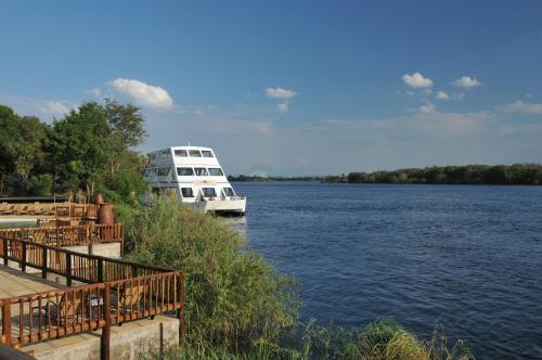 a white boat is docked on a river at The David Livingstone Safari Lodge & Spa in Livingstone