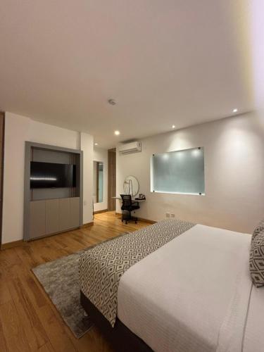 a bedroom with a bed and a flat screen tv at Casa Aurora Luxury Hotel in Cali