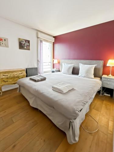 - un grand lit dans une chambre dotée d'un mur rouge dans l'établissement Charmant logement avec vue jardin - proche du métro, à Asnières-sur-Seine