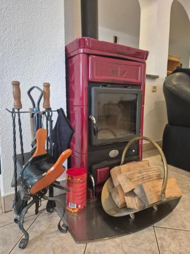 a red woodburning stove with a chair and a chair at Bella Hiša in Sromlje