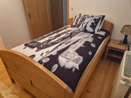 a bed with a black and white comforter and pillows at Bella Hiša in Sromlje