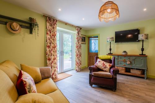 a living room with a couch and chairs and a tv at Tredodridge Barn Retreat in Saint Nicholas