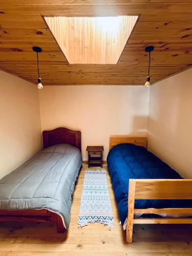 a bedroom with two beds and a wooden ceiling at Vintage Surf Pichilemu in Pichilemu
