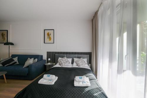 a bedroom with a bed and a blue couch at Apartamenty Florina Q4Apartments in Łeba