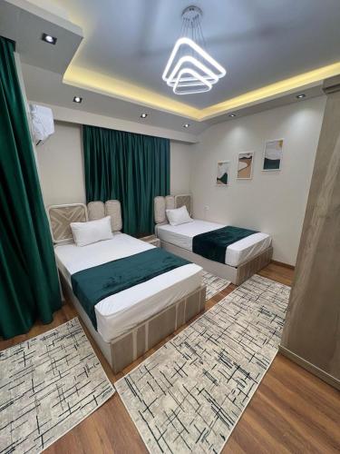 two beds in a room with green curtains at فيلا في مدينتي in Madinaty