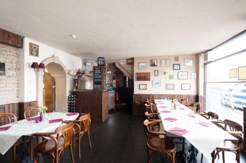 a row of tables in a restaurant with white tables and chairs at Town House Rooms in Hastings