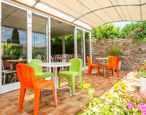 a patio with colorful chairs and tables on a patio at Bel Ombra Hôtel in Bandol