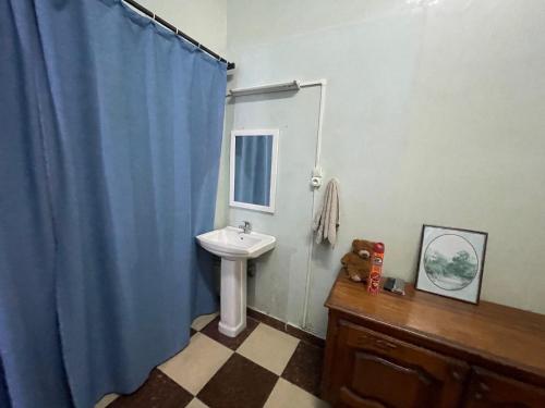 a bathroom with a sink and a blue shower curtain at 1st Floor on Bd Joffre in Toamasina