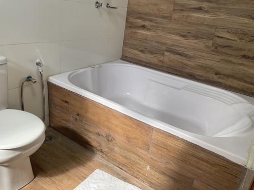 a bathroom with a white toilet and a bath tub at Espaço Alvorada com Banheira ,agendamento das atividades, café da manhã no centro in Brotas
