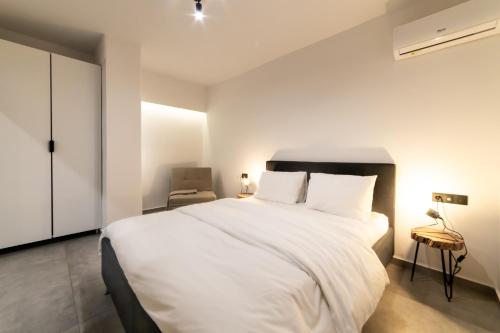 a bedroom with a large white bed and a chair at Athenian Kolonaki Apartment in Athens