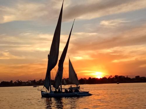 a boat with sails in the water at sunset at جزيرة العوامية in Luxor