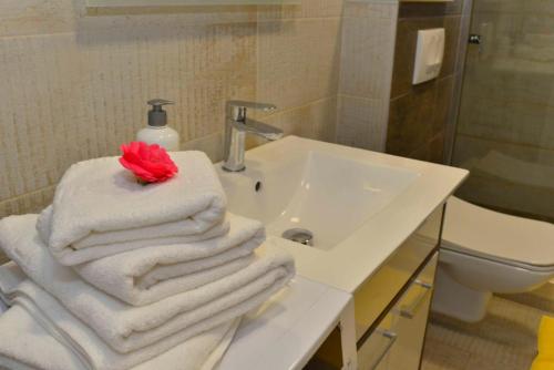a bathroom with white towels and a sink with a red flower at Apartments Boka bay in Kotor