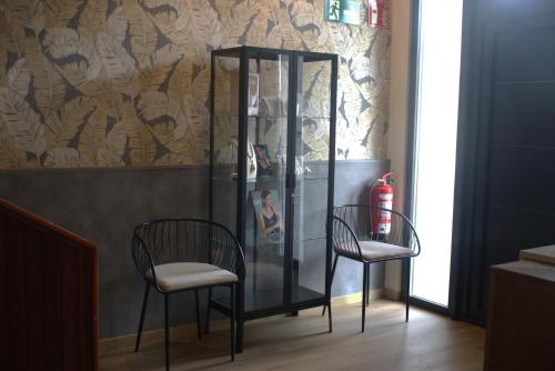 two chairs and a glass case in a room at Hotel Bermeo in Bermeo