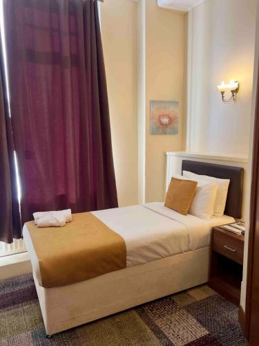 a bedroom with a bed with a purple curtain at Relax Inn Newcastle in Birtley