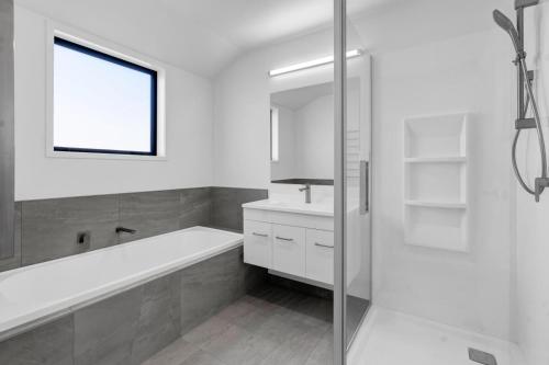 a white bathroom with a tub and a sink at Family home, Game Zone & Outdoor Fireplace- Sleeps 10 in New Plymouth