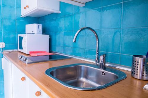 kuchnia ze zlewem i niebieską ścianą wyłożoną kafelkami w obiekcie Oriente Suites w Madrycie