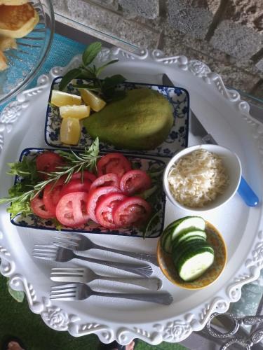 a plate of food with tomatoes and cheese and a pickle at Addo River Den in Gqeberha