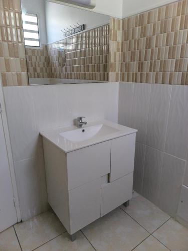 a white bathroom with a sink and a mirror at Gite Beauvallon in Basse-Terre