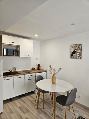 une cuisine avec des armoires blanches et une table et des chaises dans l'établissement Studio cosy à 5min à pieds de la gare, à Valenciennes