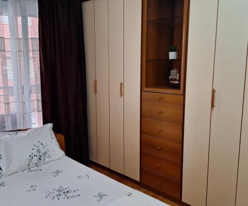 a bedroom with a bed and a cabinet and a window at Morina Apartment Prishtina in Pristina