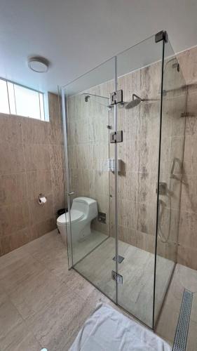 a bathroom with a glass shower with a toilet at Hospedaje La Angostura in Ica