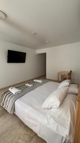 a bedroom with a large white bed with a flat screen tv at Hospedaje La Angostura in Ica