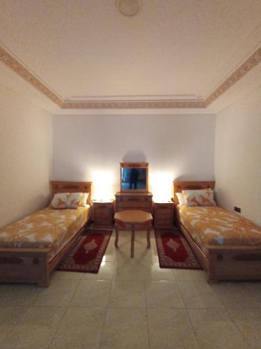 a room with two beds and a table in it at résidence sara in Fez