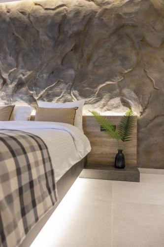 a bedroom with a bed with a stone wall at Polyzos Luxury Suites Meteora #3 - Adults Friendly in Kalabaka