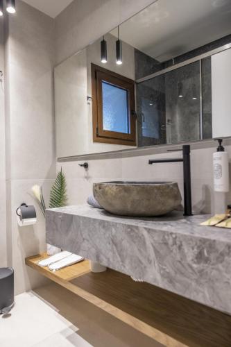 a bathroom with a sink with a large stone bowl at Polyzos Luxury Suites Meteora #3 - Adults Friendly in Kalabaka
