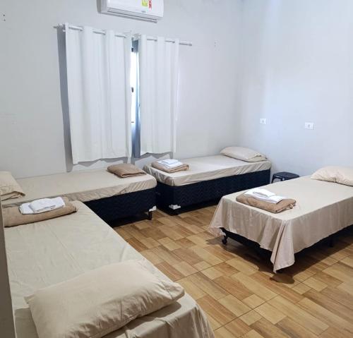 a room with three beds in a room at Hotel Tucano in Inocência