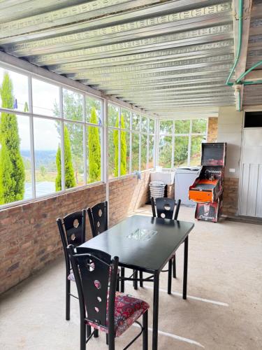 a dining room with a table and chairs and windows at Chalet Familiar Delpilar, Full equipado, zona de Jacuzzi! in Sogamoso