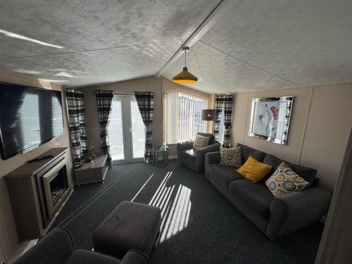 a living room with a couch and a tv at Golden Palm Resort - The Meridian - Coastal Caravan Breaks in Chapel Saint Leonards