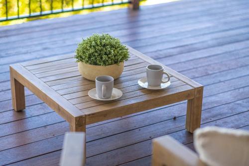 a wooden coffee table with two cups and a potted plant at Mountain Retreat Scenic Getaway with BBQ in Mount Tamborine